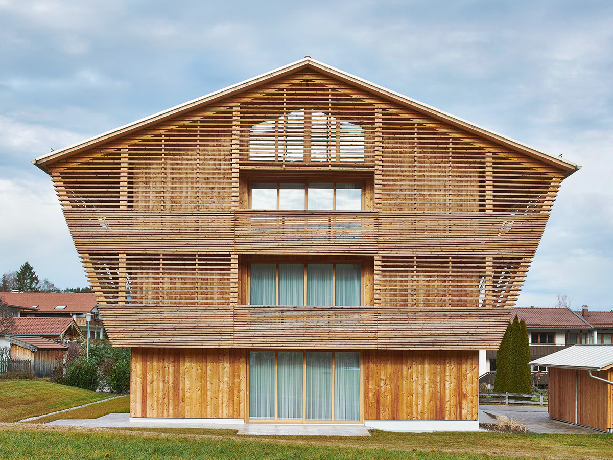 Ein zweistöckiges Haus mit Holzfassade, links ist eine Garage angebaut.